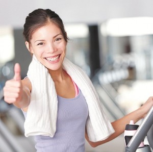 Happy fitness woman thumbs up in gym